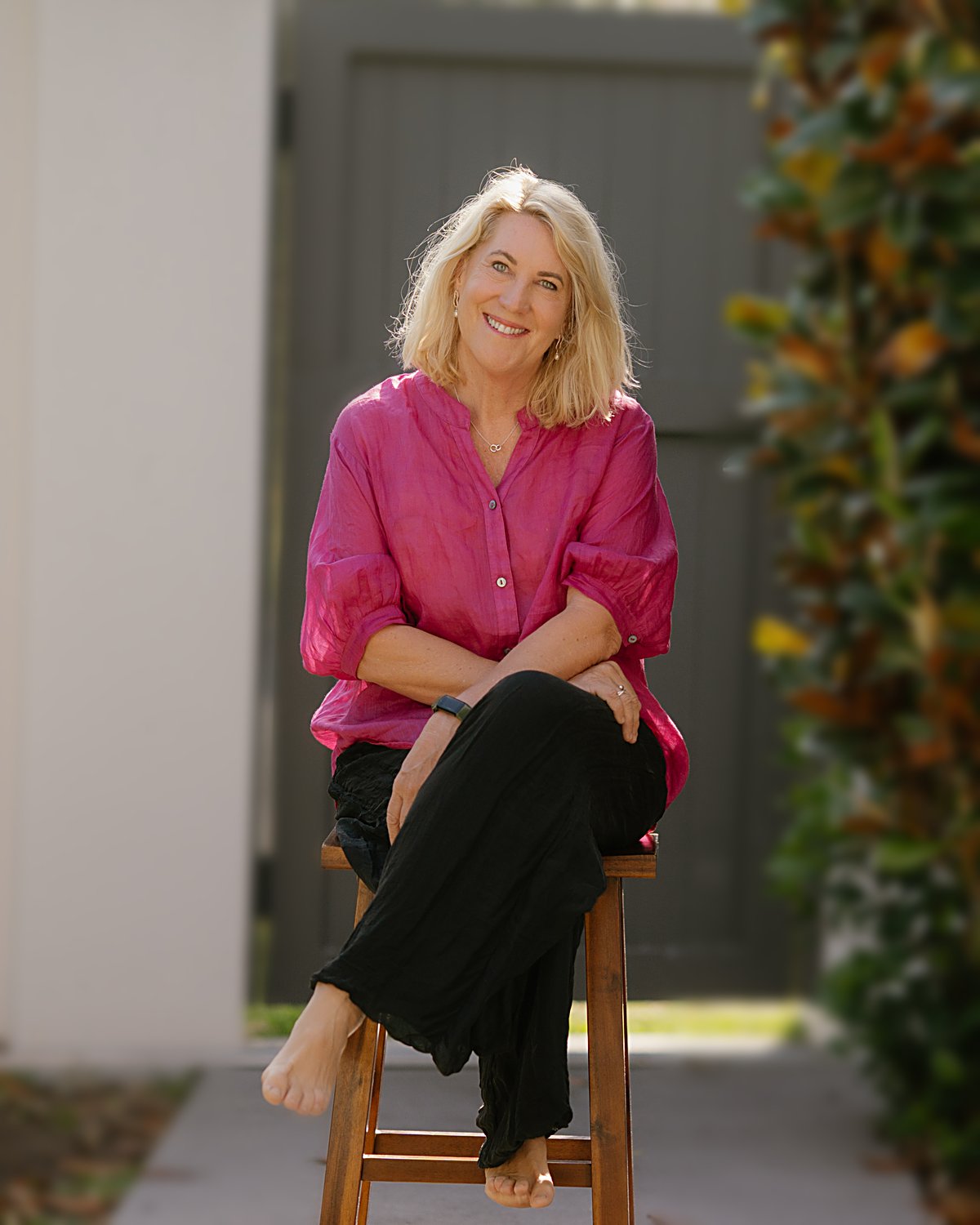 Debbie Thompson smiling, sitting on a stool in her garden