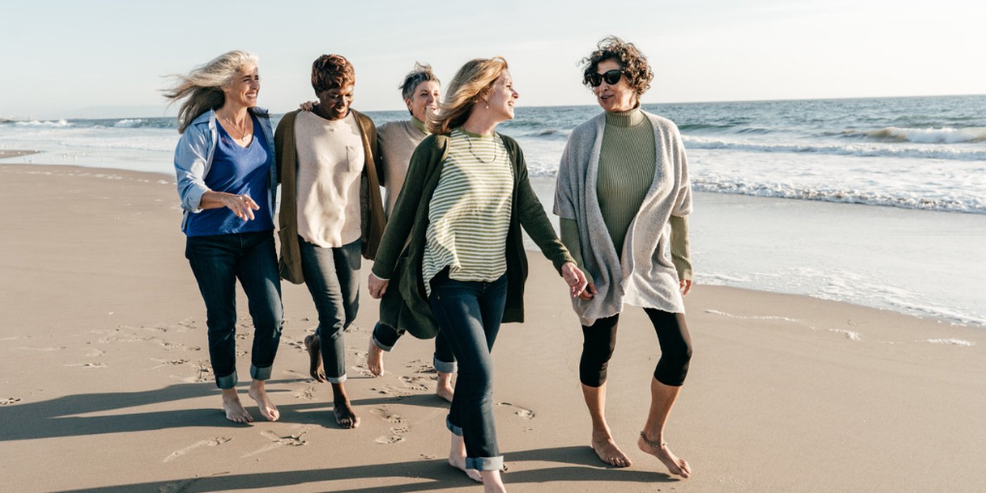 A group of women walking and laughing on the beach